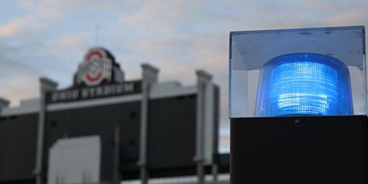 a light atop a police cruiser, with Ohio Stadium in the background