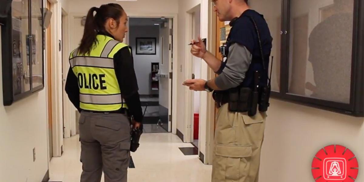 a police woman and a man in a hallway, discussing safety techniques